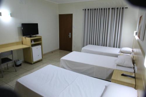 a hotel room with two beds and a television at Savana Park Hotel in Andradina