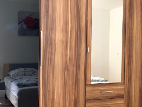 a wooden cabinet with a mirror next to a bed at Ferienwohnung Familie Hinrichs in Dorn-Dürkheim