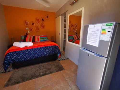 プレトリアにあるThe Aces - NUDE - SunEden Family Naturist Resortのベッド1台、冷蔵庫が備わる小さな客室です。