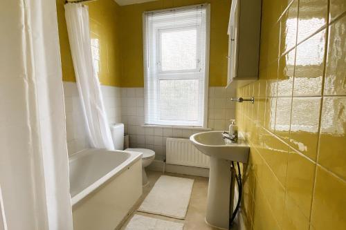 ein Badezimmer mit einer Badewanne, einem Waschbecken und einem WC in der Unterkunft Spacious 6 Bedroom House Close to Beaches and Town in Bournemouth