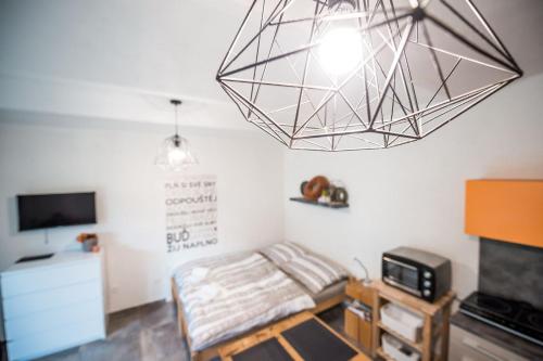 Habitación con cama, TV y lámpara de araña. en Apartmán ve Dvoře en Ratíškovice