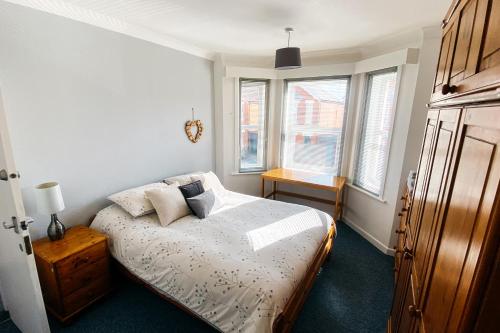 a bedroom with a bed and two windows at Spacious 6 Bedroom House Close to Beaches and Town in Bournemouth