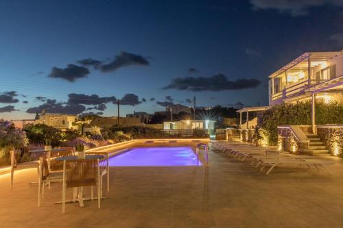a swimming pool at night with a table and chairs at Sea Wind Villas and Suites in Tourlos