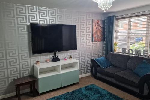 a living room with a couch and a flat screen tv at Well Furnished 3 Bedroom House in a cosy estate in Bolton in Bolton