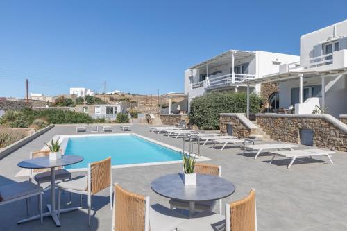 a patio with tables and chairs next to a swimming pool at Sea Wind Villas and Suites in Tourlos