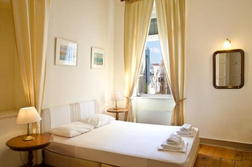 um quarto com uma cama branca e uma janela em Hotel Omiros em Ermoupoli