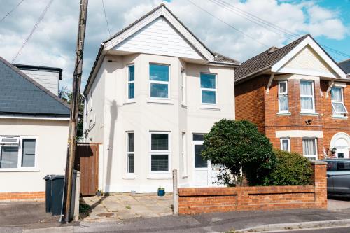 a white house with a brick fence in front of it at Spacious 6 Bedroom House Close to Beaches and Town in Bournemouth