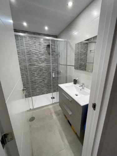 biała łazienka z prysznicem i umywalką w obiekcie Duplex RiAnna w Costa Teguise