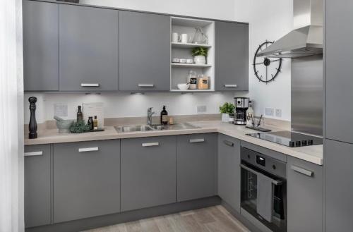 a kitchen with white cabinets and stainless steel appliances at Stylish Birmingham City Centre Apartment in Birmingham