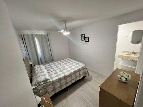 Un pequeño dormitorio con una cama y una mesa. en Residence club Praia dos Anjos, en Arraial do Cabo