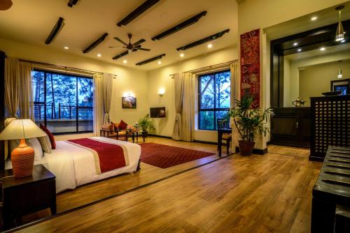 a bedroom with a bed and a desk and windows at Gokarna Forest Resort Kathmandu in Kathmandu