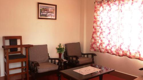 a waiting room with chairs and a table and a window at K & K INN in Cherrapunji