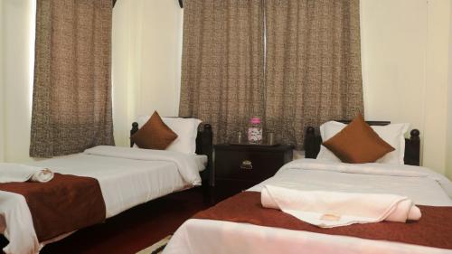 a hotel room with two beds and curtains at K & K INN in Cherrapunji