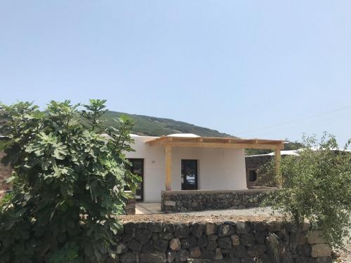 a small white house with a stone wall at La Grotta di benikula' in Pantelleria