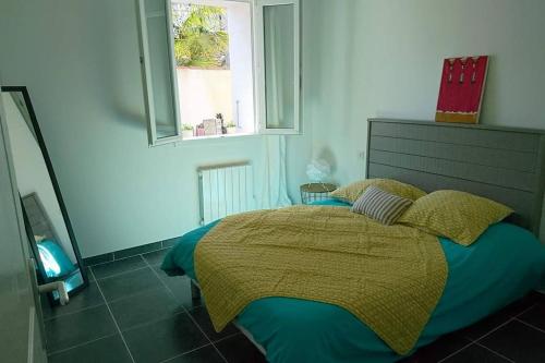 - une chambre avec un lit doté d'une couverture jaune et d'une fenêtre dans l'établissement Charmante Maison Oléronnaise ALOCEANE, à Saint-Denis-dʼOléron