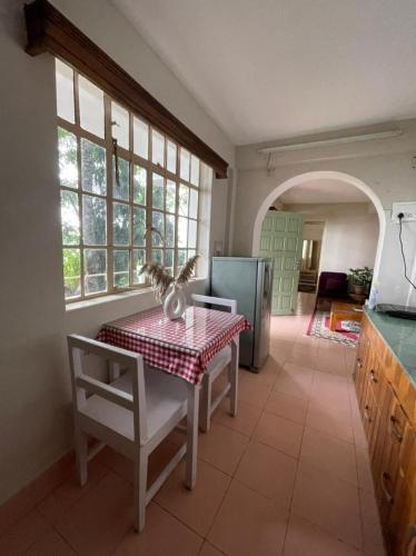 a kitchen with a table and a refrigerator in a room at THE GINGKO EYRIE in Kalimpong