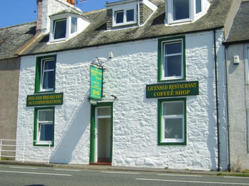 a white building with green trim on a street at The Merchants House in Cairnryan