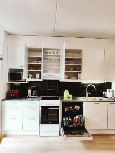 a kitchen with white cabinets and an open dishwasher at Joutjärven Studio Apartment in Lahti
