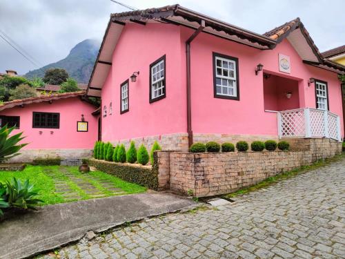 une maison rose dans une rue pavée dans l'établissement Pousada Lírio do Campo, à São Pedro da Serra