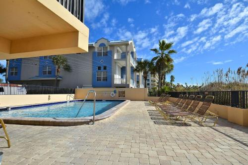 a swimming pool with chairs and a house at Villa Madeira 206 in St Pete Beach