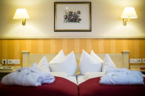 a pile of pillows on a bed in a hotel room at Hotel Hirsch in Oberstaufen