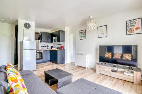 a living room with a couch and a kitchen at Le Convertible - Proche Disney - Parking Privé in Chalifert