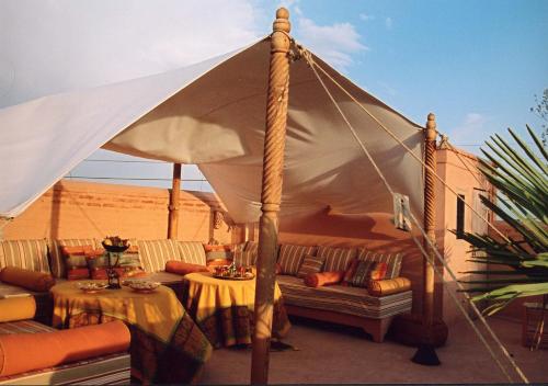 a tent with a couch and tables in the desert at Riad Herougui in Marrakesh