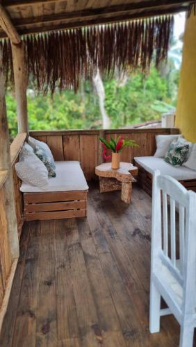 um alpendre exterior com 2 camas e uma cadeira em Casa Namoa Pousada na Ilha de Boipeba