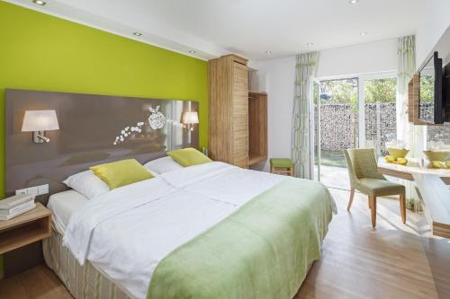 Hotel Schönau في لينداو: غرفة نوم بسرير كبير وجدار أخضر