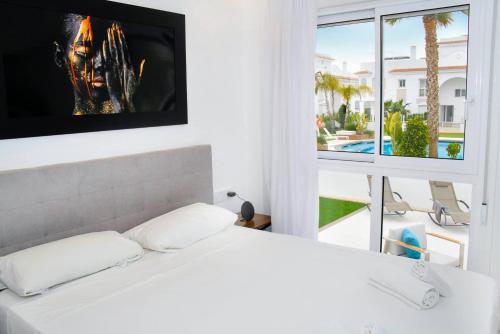 a bedroom with a white bed and a large window at Premium Ferienwohnung: Allegra - Alba - Residential in Ciudad Quesada