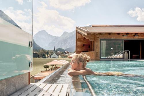 a woman in a swimming pool at a resort at Das Karwendel - Ihr Wellness Zuhause am Achensee in Pertisau