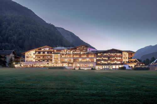 a large building with a grass field in front of a mountain at Das Karwendel - Ihr Wellness Zuhause am Achensee in Pertisau