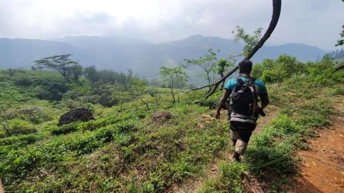 a man with a backpack walking down a dirt trail at Galaha Eco Camping 1 in Kandy