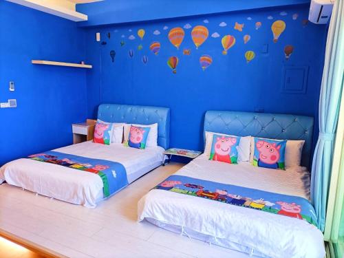 two beds in a room with blue walls and hot air balloons at 愛海居民宿Love in Taitung City