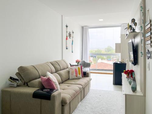a living room with a couch and a large window at Estada inesquecível 09 Bacutia/Guarapari Premium in Guarapari