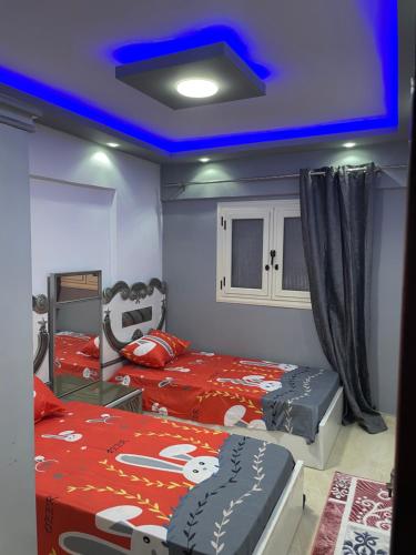 a bedroom with two beds and a blue ceiling at Alzohour Family condo with panoramic sea view in Alexandria