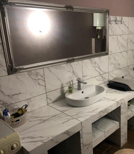 La salle de bains est pourvue d'un lavabo et d'un grand miroir. dans l'établissement Квартира в центре города, à Ouman