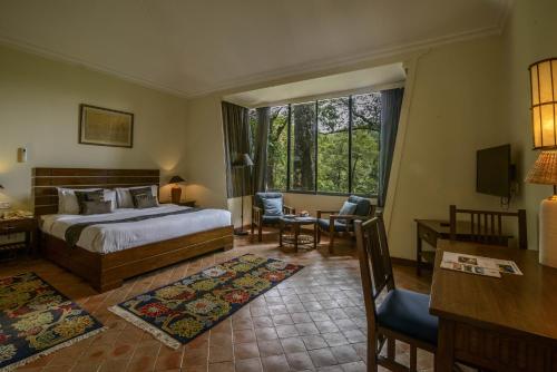 a bedroom with a bed and a desk and a window at Gokarna Forest Resort Kathmandu in Kathmandu