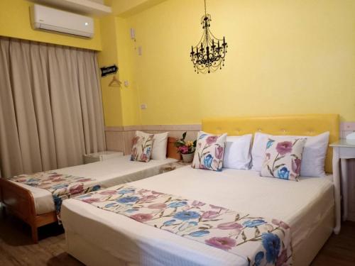 two beds in a hotel room with a chandelier at 愛海居民宿Love in Taitung City