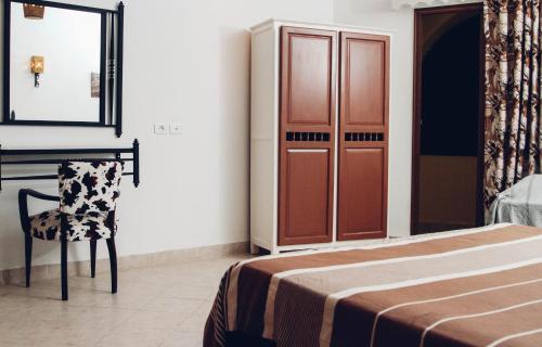 a bedroom with a bed and a desk and a chair at Résidence Le Ruisseau in Tozeur