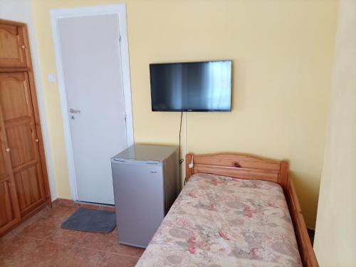 - une chambre avec un lit et une télévision murale dans l'établissement Квартири - стаи за гости, Ахтопол, à Ahtopol
