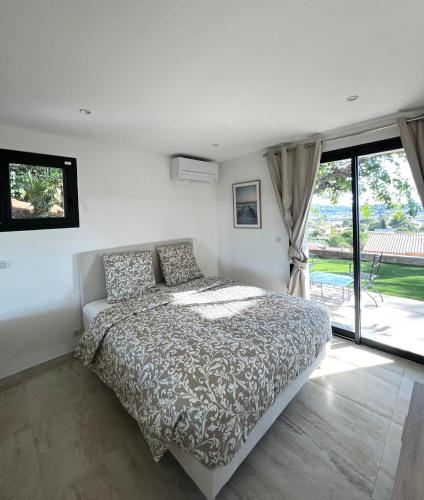 une chambre avec un lit et une grande fenêtre dans l'établissement Appartement des Oliveraies, à La Valette-du-Var