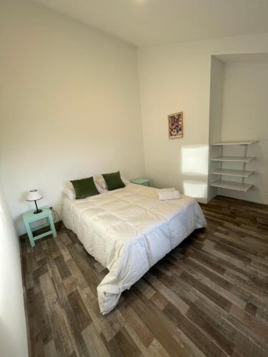 1 dormitorio con 1 cama blanca grande y suelo de madera en Bella Vista 5 en Esquel