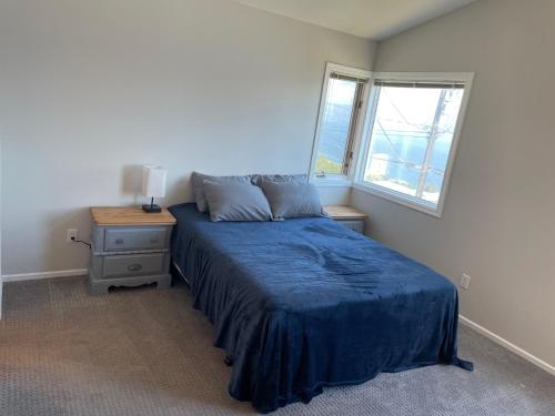 Un dormitorio con una cama azul y una ventana en Blue View Family Getaway, en Peachland