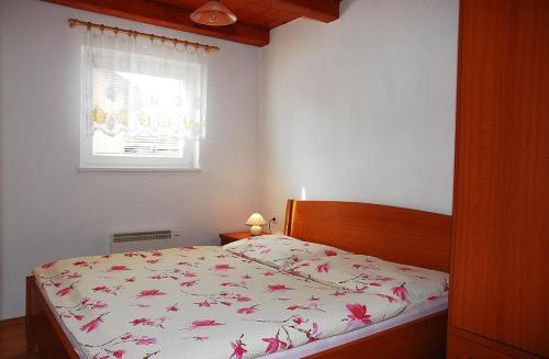 1 dormitorio con 1 cama con colcha de flores y ventana en Apartment chatky Aquaduo, en Liptovská Sielnica