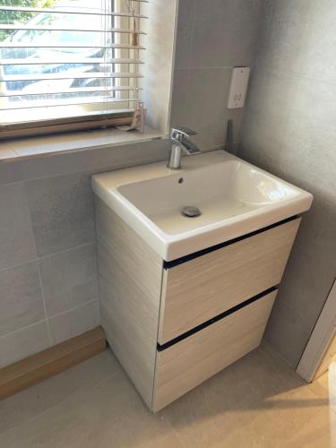 a bathroom with a white sink and a window at Crab Cottage in Wells next the Sea