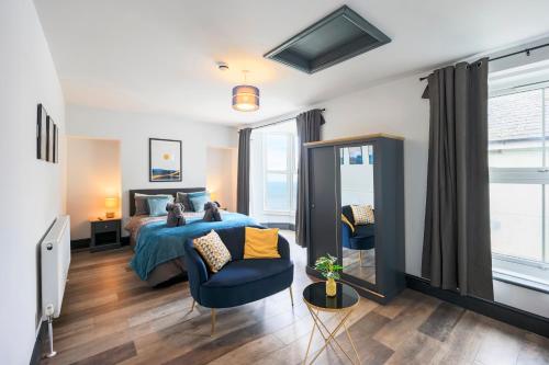 ein Schlafzimmer mit einem Bett und einem blauen Stuhl in der Unterkunft Seafront apartment with balcony, parking and sea views in Aberystwyth