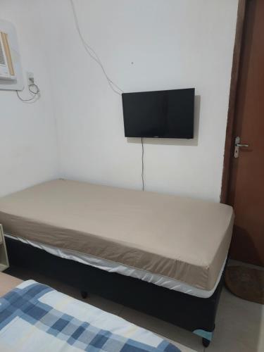 a bed in a room with a tv on the wall at Bonito é ser Feliz in Recife