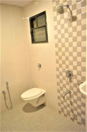 a bathroom with a toilet and a window and a sink at Hotel Visau,Shirdi in Shirdi
