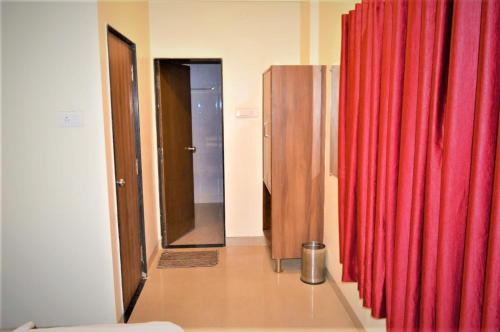 a room with red curtains and a hallway with a door at Hotel Visau,Shirdi in Shirdi